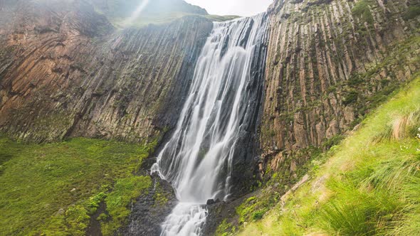 Timelapse of a High Mountain Waterfall in the Rays of Sunlight Against the Background of Rocks and