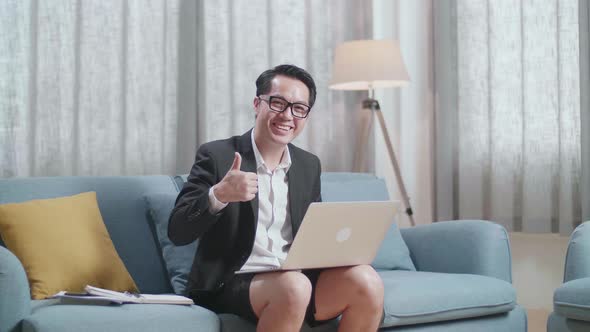 Asian Businessman Smiling And Showing Thumbs Up Gesture To Camera While Working With A Laptop