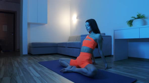 Fitness at Home in Blue Lighting  Young Woman Doing Fitness Exercises on Yoga Mat