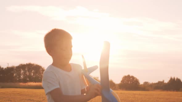 Little boy plays with a toy plane in a field at sunset. Childhood, freedom, inspiration concept.