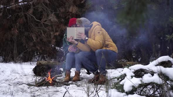 Guy and Girl Read a Book in Winter in the Forest