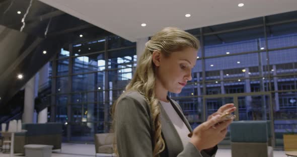 Businesswoman using mobile phone in the lobby at office 4k