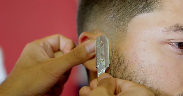 Barber trimming client hair with straight razor at barber shop 4k