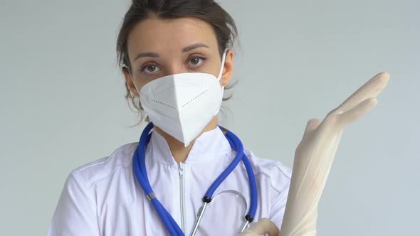 Female Doctor is Putting Off Protective Blue Gloves Isolated on White Background After Some Medical