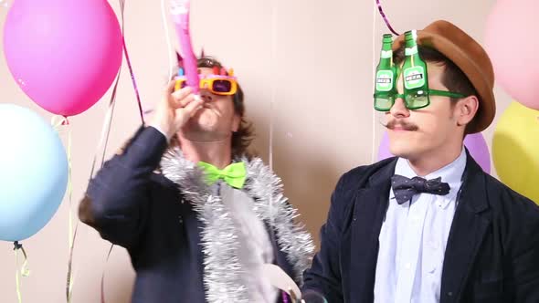 Party guys having fun with funny props in photo booth