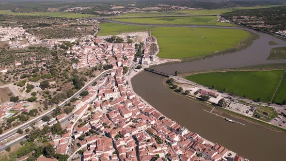 Birds eye view of riverside parish townscape and rice paddy fields alongside sado river channel.