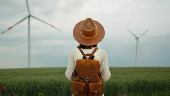 A young woman in a hat and with a backpack with alternative energy generation