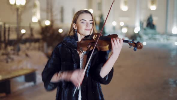 Young lady playing the violin on the street. Violinist playing in the middle of the street 