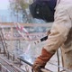 Welder at Construction Site Is Welding Pipe with Electrode in Helmet. - VideoHive Item for Sale