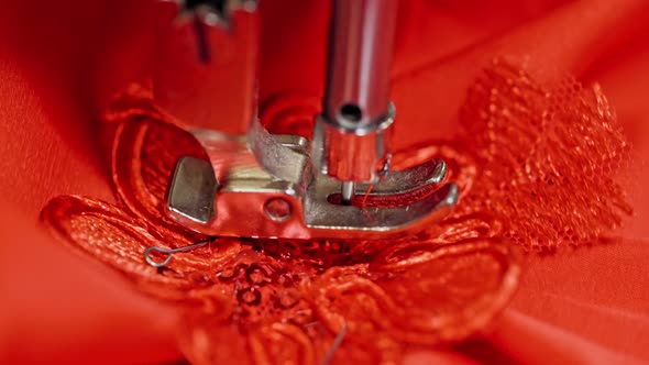 Close-up needle of a sewing machine working on red fabric. 