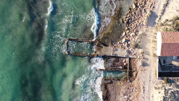 Eroded building at Trenc Beach in Mallorca Spain with concrete foundation pounded by waves, Aerial t