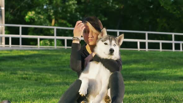 Beautiful Young Woman Playing with Funny Husky Dog Outdoors in Park