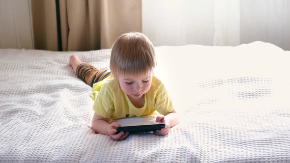 Child Lying on Bed with Cell Phone