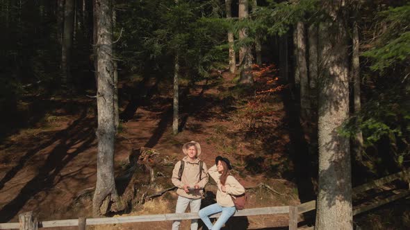 Aerial Slow Motion View of Couple Hikers Man and Woman on Shore of Beautiful Famous Mountain Lake