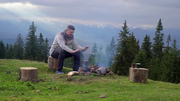 A Man Near a Fire in the Mountains