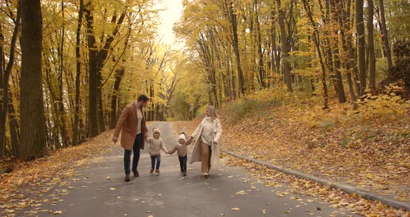 Young Family Walks Along the Road Holding Hands