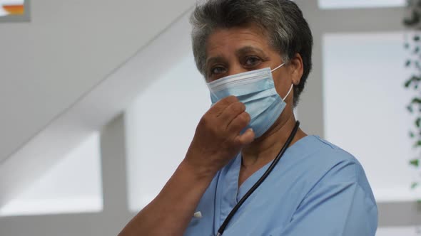 Portrait of senior african american female doctor wearing face mask looking at camera and smiling