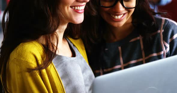 Smiling female executives discussing over laptop during meeting