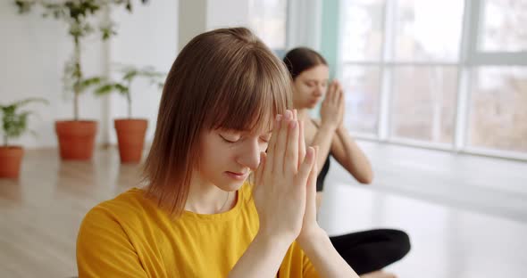 Relaxed Young Women in Sportswear is Meditating in Lotus Position Yoga Class