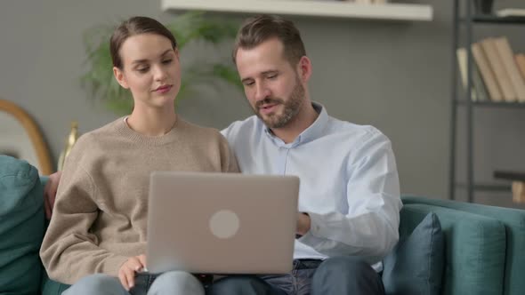 Couple Working on Laptop Together While Sitting on Sofa