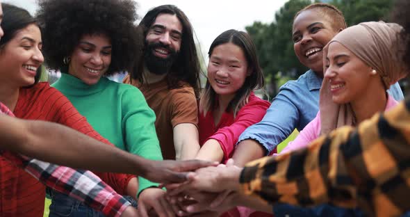 Young multiethnic people having fun stacking hands outdoor