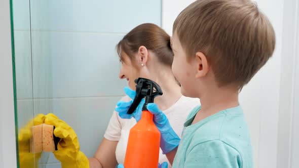 Little Toddler Boy Applying Chemical Detergent From Spray While Mother Rubbing and Cleaning Bathroom