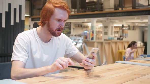 Redhead Beard Man Sitting in Cafe Upset By Loss of Work