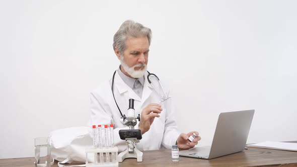 Senior Male Doctor Examining Studying the Coronavirus Tests in Tube