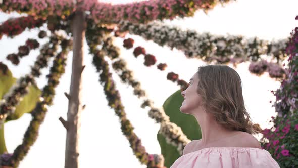 Girl Admires Hanging Flowers in a City Park