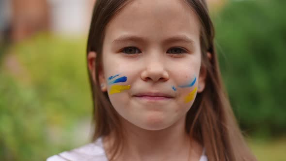 Pretty Girl with Brown Eyes and Face Painting Looking at Camera Smiling