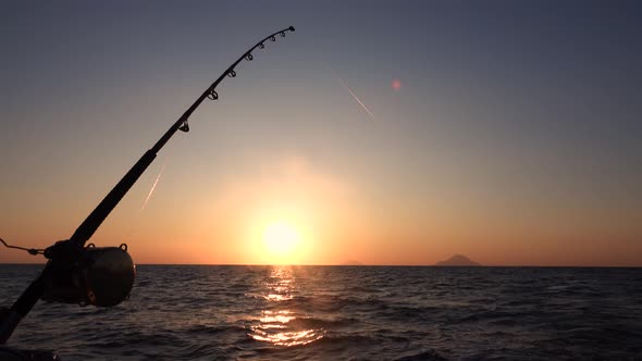 Fishing Rod on Moving Sailing Yacht, Lipari Islands in Distance. Mediterranean Sea. Sunset, Colorful