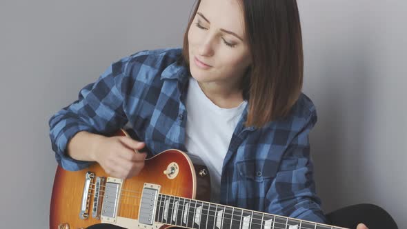 Woman playing guitar wearing blues shirt enjoying song. Music Industry concept