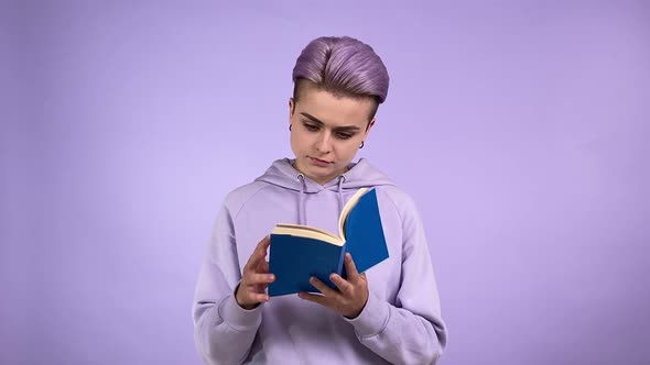 Female Student Turning Pages Reading Book Isolated on Purple Indoors