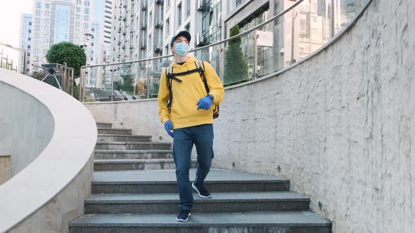 Happy Young Delivery Man with Yellow Uniform and Backpack Actively Dancing While Walking Down the