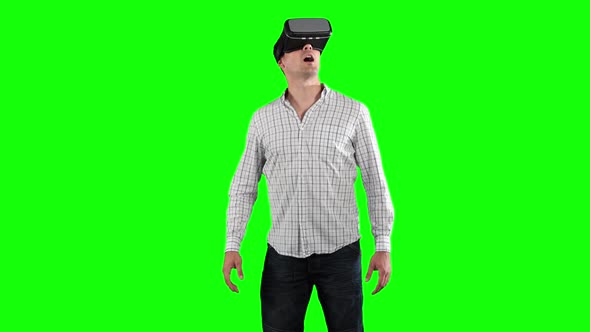 a Caucasian man wearing 3D goggles in a green background