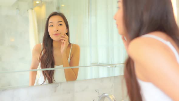 Young asian woman check her face on mirror