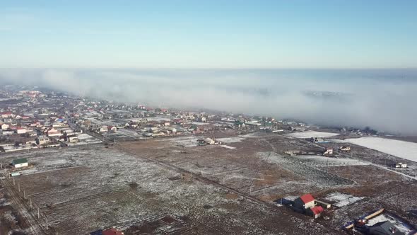 Aerial View on Landscape Scene with Fog Fast Moving over the Small Town in Winter