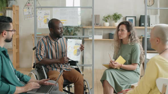 Afro Man in Wheelchair Presenting Business Plan at Office Meeting