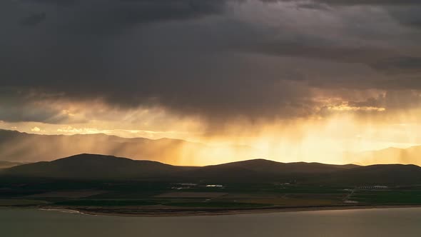 Sun rays beaming light through rainstorm moving over the farmland by Utah Lake