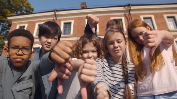 Group of Diverse Children Showing Dislike with Thumbs Down Standing Outdoors