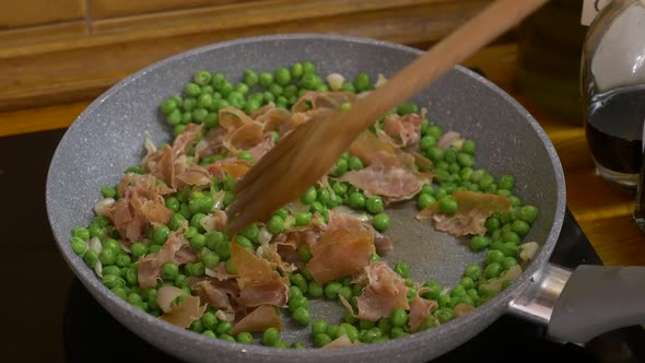 cooking peas with ham and turning them with wooden spoon