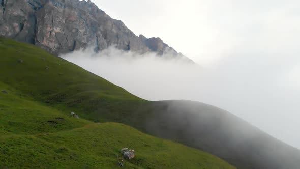 Green Landscape Grassy Meadow Next To Mountain at Height of the Cloud