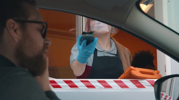 Bearded Man Driver in Car Paying with Credit Card for Fast Food Order at Drive Thru Counter