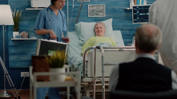 Doctor and Nurse Doing Checkup Visit for Ill Patient in Hospital Bed