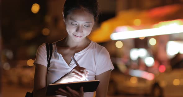 Woman using digital tablet with pen at night 