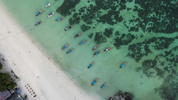 top down view of longtail boats docked on white sand beach in Koh Lipe Thailand, aerial, zoom out, c