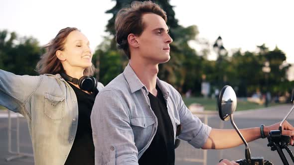 Young Couple Enjoying Riding on Electric Minibike Through Park in Summer