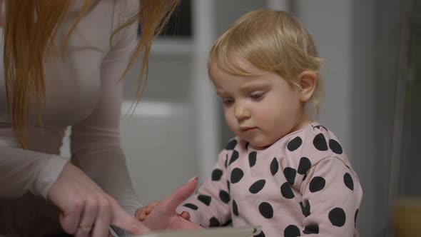 Curious Baby Daughter Looking at Tablet Screen As Unrecognizable Mother Scrolling Surfing Internet