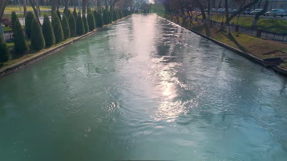 City canal with slow water flow surrounded by trees