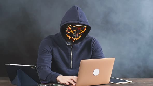 Hacker in a Hood, a Hacker on a Dark Smoky Background